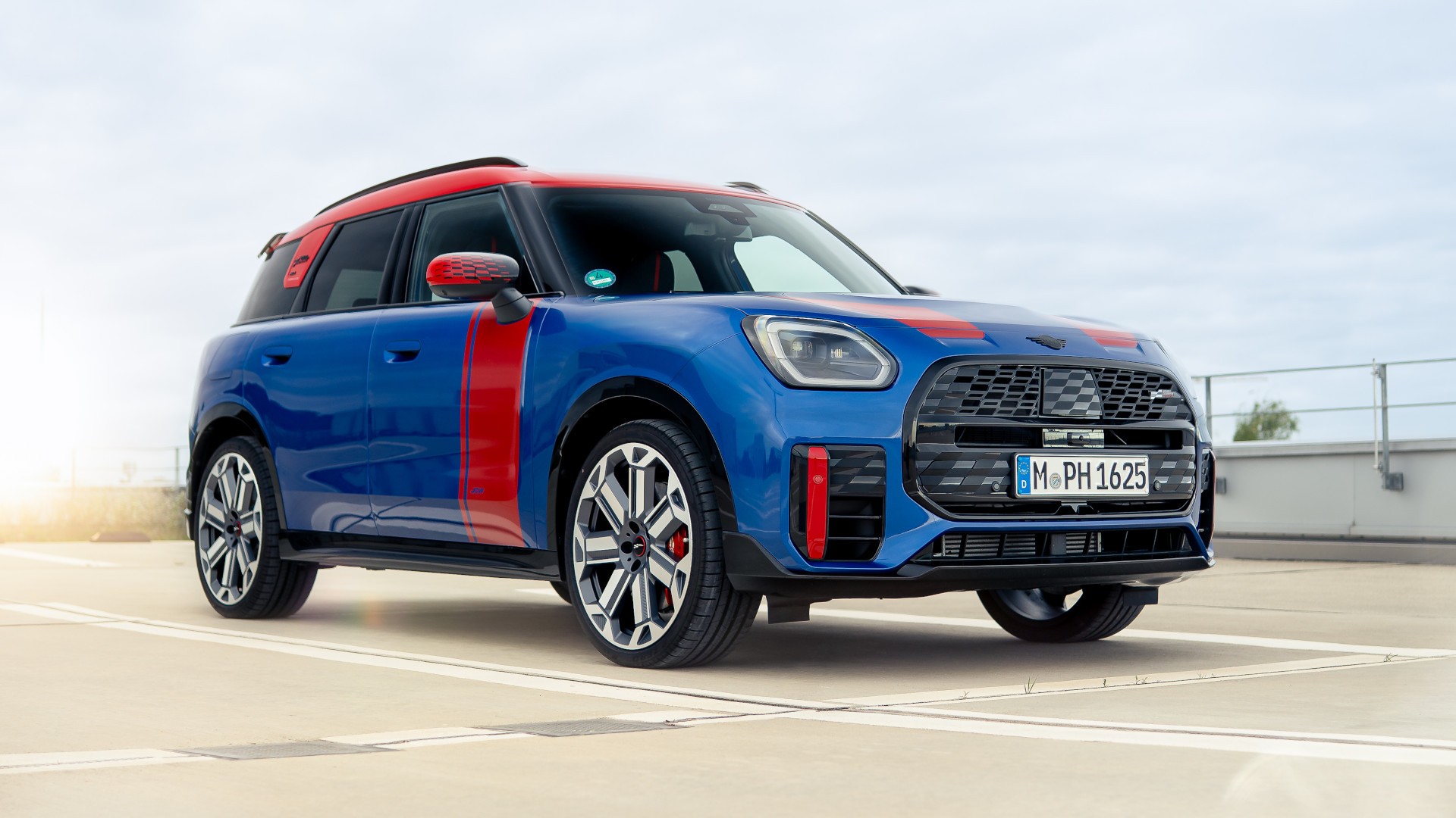 MINI Countryman in blazing blue mit JCW Folierung in chilli red, Frontalansicht.